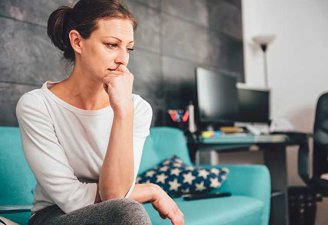 A woman sitting on the couch looking worried