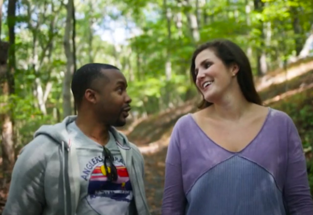 A man and woman walk through the woods