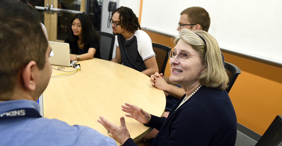 Female faculty talking with graduate students.