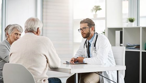 Doctor speaks with older couple in a sunny office