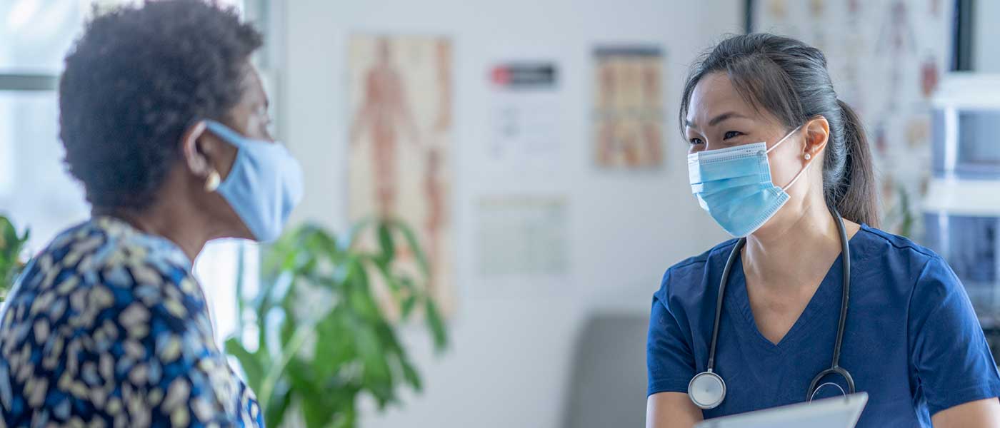 Doctor speaking with her patient in a sunny exam room.