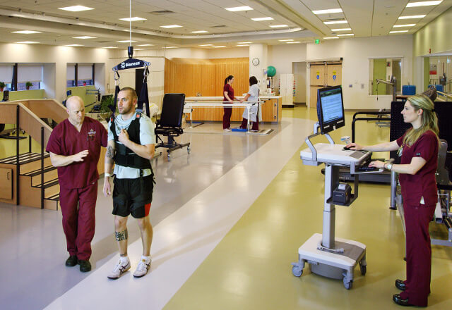 Physical therapists assisting patient with mobility device.