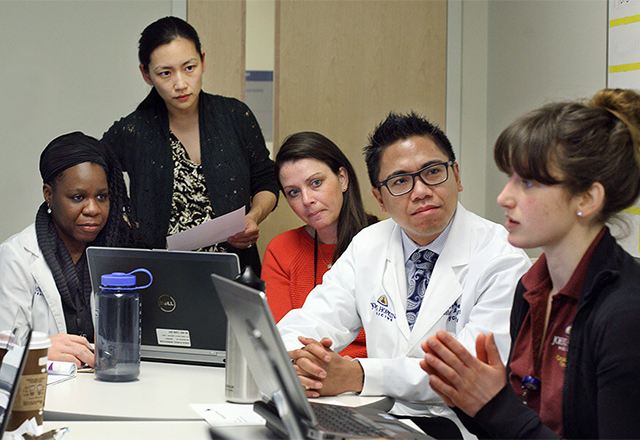 Faculty sit at a table in conversation.