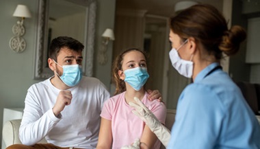 Father and teen talk to pediatric home health nurse